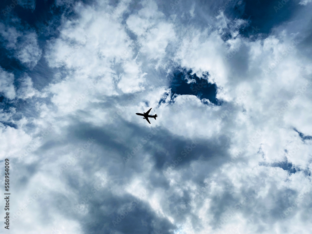 Dramatic photo of solo passenger plane flying overhead against a dramatic cloud formation