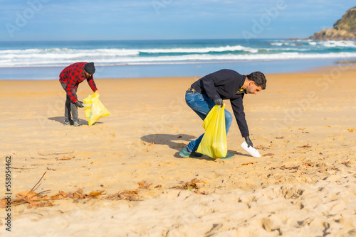 Volunteers collecting plastic from the sand on the beach. Ecology concept, sea pollution