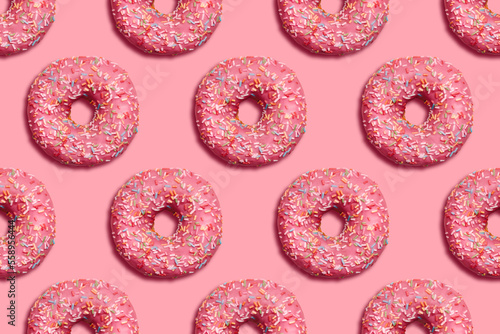 Flat lay donuts seamless pattern on pink background. Sweet glazed sprinkles pastry. Top view photo in minimal style