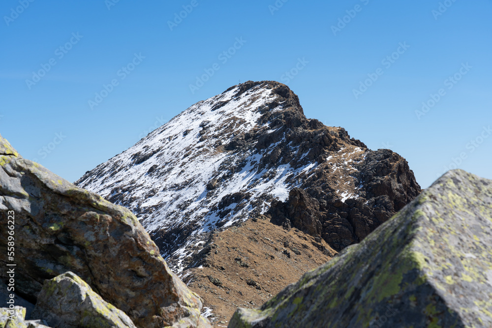 big rocks foreground , mountain ridge and peak with snow background. landscape with snow covered mountain and blue sky