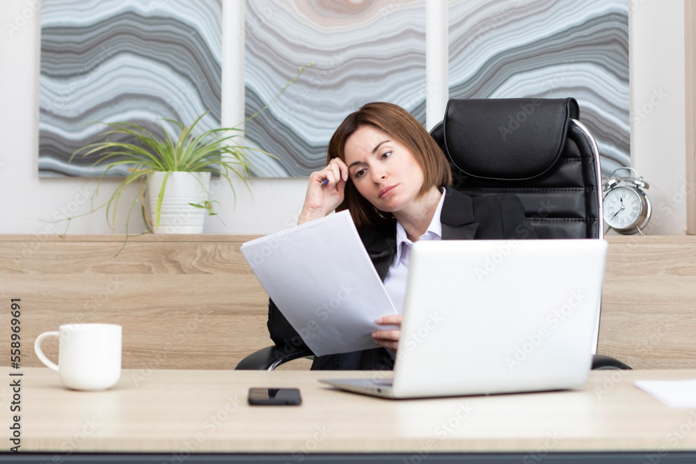 Tired frustrated and overworked business woman sitting in the office and thinking about problems in business Tired frustrated and overworked business woman sitting in the office and thinking about problems in business
