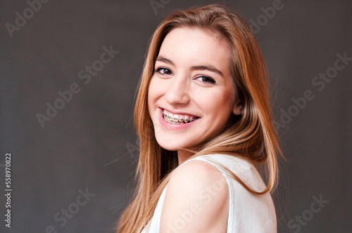 smiling girl with braces, portrait over grey background