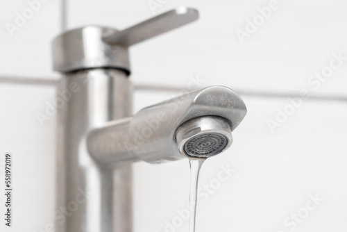 Water flows from the faucet in the bathroom. Water faucet close-up. Saving water. The faucet needs repair