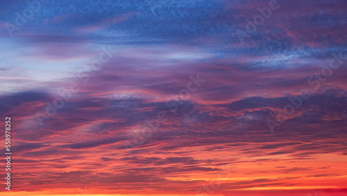 Dramatic colorful sunset sky and majestic orange sunlight clouds on blue twilight in evening time