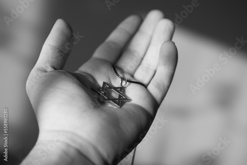 Closeup of pendant in the shape of the star of david on the hand of a man. Holocaust remembrance day. Black and white photo. photo