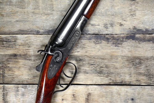 Old Vintage Classic trigger double-barreled hunting rifle on a wooden background. Smooth-bore hunting rifle.