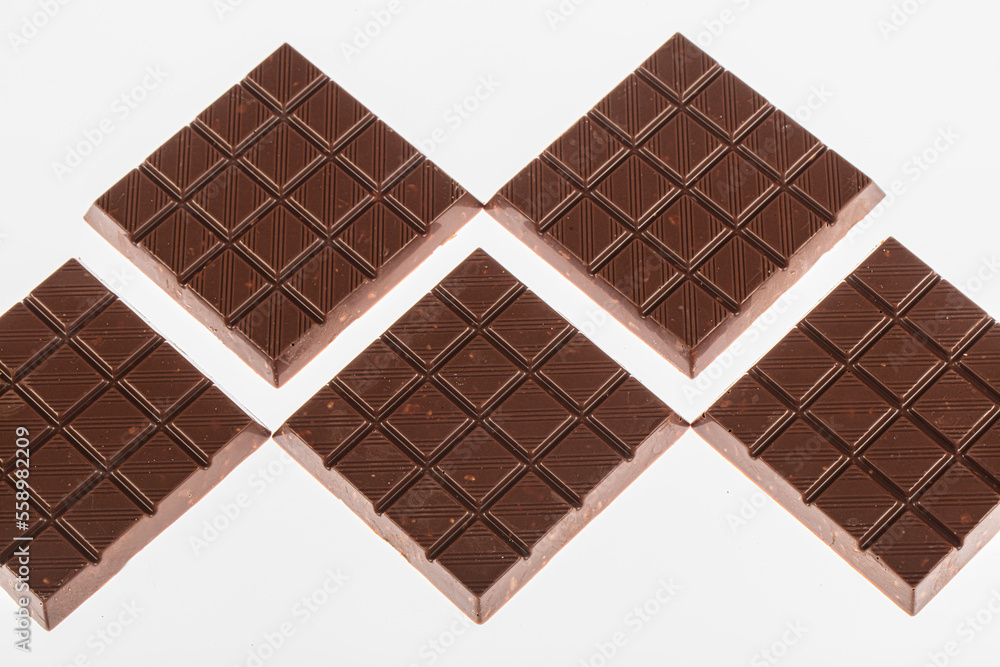 Hazelnut chocolate. Hazelnut chocolate bar pieces tower. Bars of milk and dark chocolate lying one on one. Milk chocolate with hazelnuts on a White Background.. Hazelnut chocolate. Hazelnut chocolate bar pieces tower. Bars of milk and dark chocolate lying one on one. Milk chocolate with hazelnuts on a White Background..