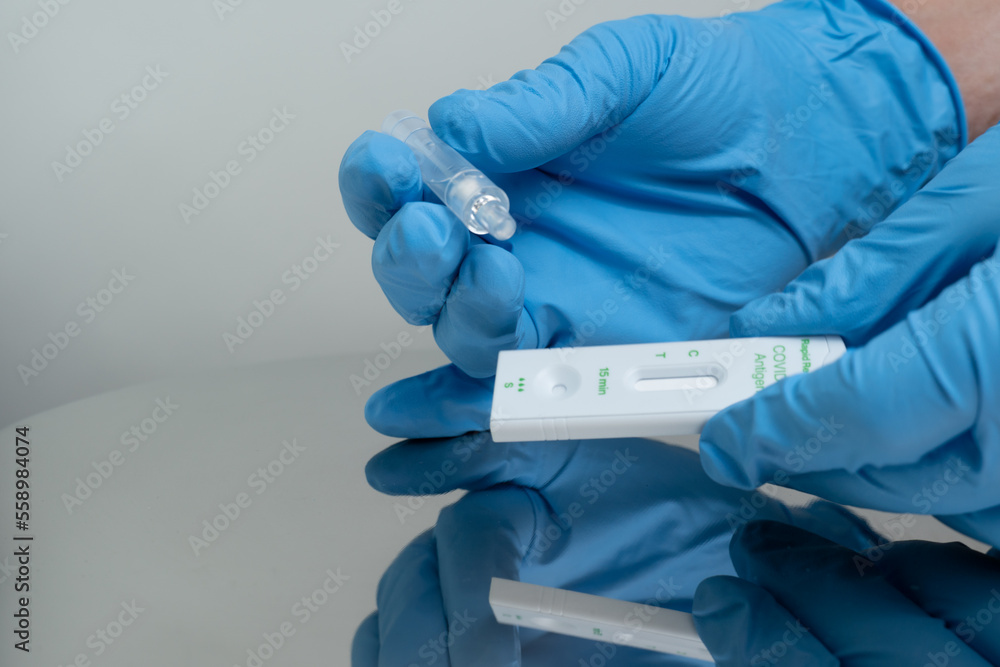 Person drops specimen test liquid in rapid test cassette for detection of Corona virus Covid-19. Personal antigen rapid self test kit for home. For in vitro diagnostic use only. Person drops specimen test liquid in rapid test cassette for detection of Corona virus Covid-19. Personal antigen rapid self test kit for home. For in vitro diagnostic use only.