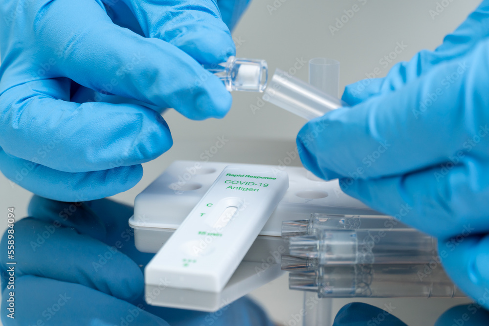 Person in blue gloves performs COVID-19 rapid test at home using personal home test kit for in vitro diagnostic use only. Person in blue gloves performs COVID-19 rapid test at home using personal home test kit for in vitro diagnostic use only.