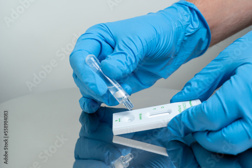 Person drops specimen test liquid in rapid test cassette for detection of Corona virus Covid-19. Personal antigen rapid self test kit for home. For in vitro diagnostic use only. photo