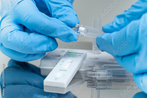 Foto Person in blue gloves performs COVID-19 rapid test at home using personal home test kit for in vitro diagnostic use only