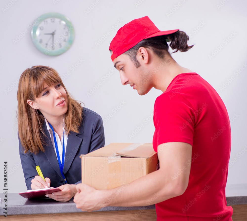 Young male courier delivering box to hotel's reception Young male courier delivering box to hotel's reception