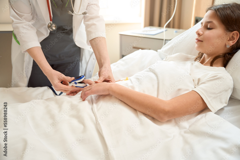 Obraz premium Health worker uses small sphygmomanometer to measureblood pressure teenage girl