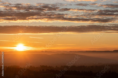 sunrise with sun shining into the camera in germany swabia with hazy landscape