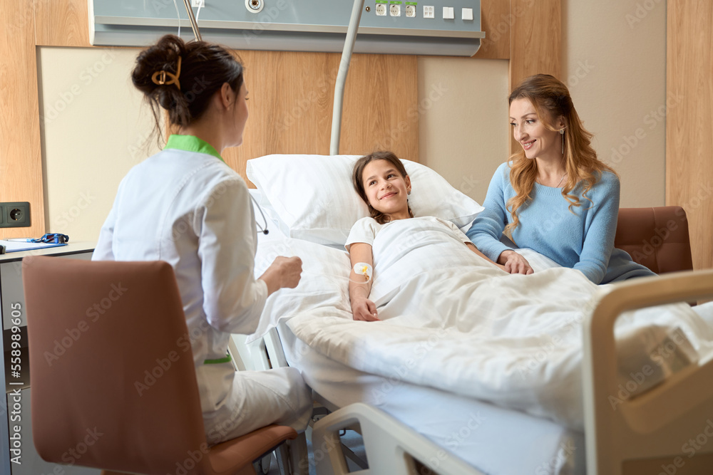 Obraz premium Young patient, her mother and female doctor communicate in hospital room