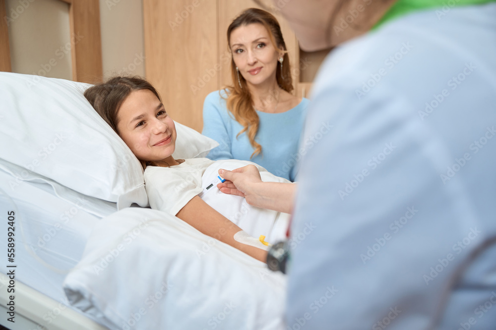 Doctor and mother are sitting at bedside of teenager girl Doctor and mother are sitting at bedside of teenager girl