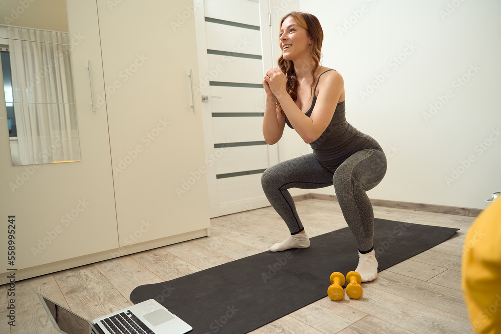 Obraz Joyful sporty lady doing lower-body workout at home fototapeta, plakat