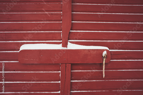 detail of red wooden gate while snowing