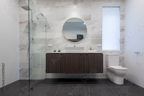 modern interior of new bathroom with shower, vanity, stylish tiles and toilet