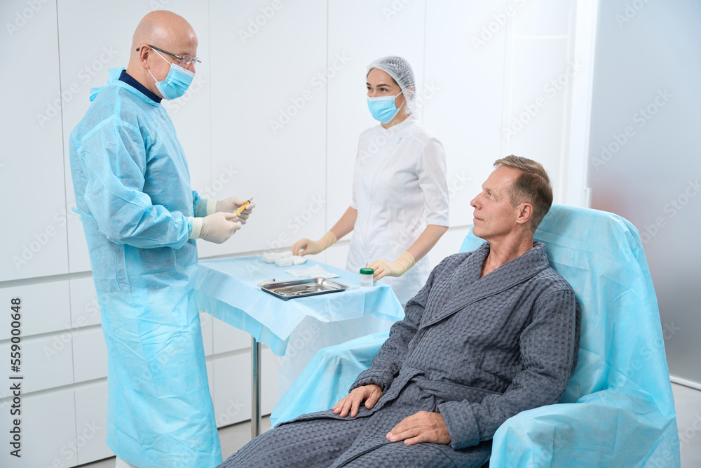 Serene middle-aged man waiting for doctor to start the procedure Serene middle-aged man waiting for doctor to start the procedure