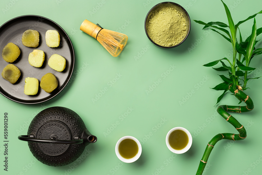 matcha tea with teapot and tea cups on green background with copy space
