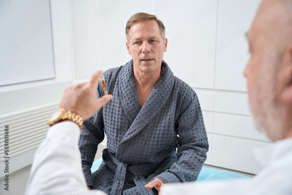 Middle-aged man communicates with a doctor in a medical center Middle-aged man communicates with a doctor in a medical center