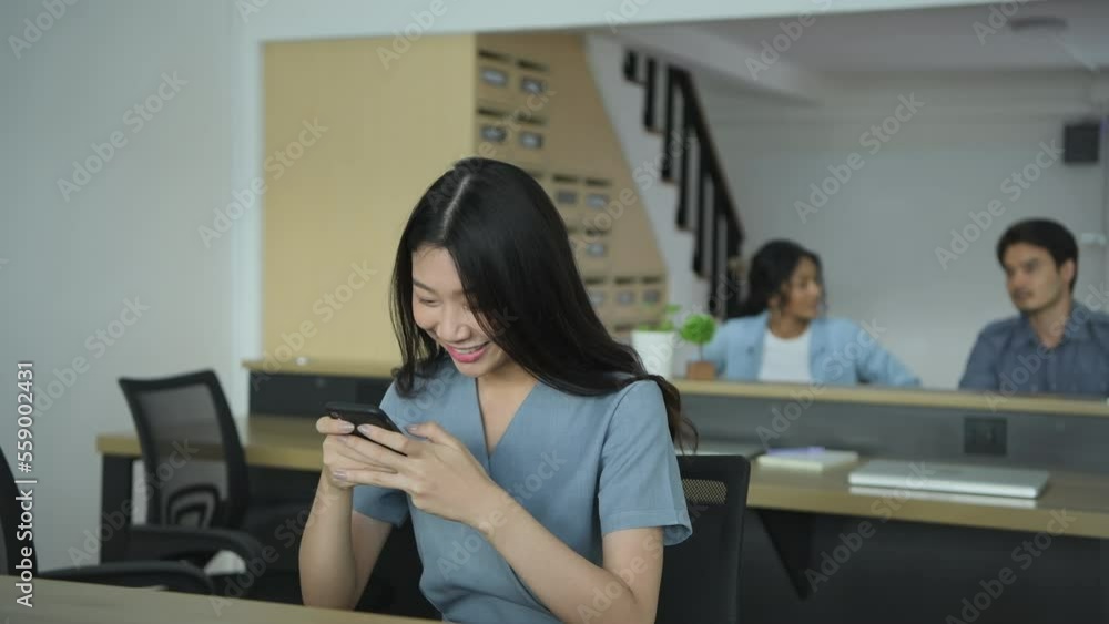 Business concept of 4k Resolution. Asian girls are happily using the phone in the office. Business concept of 4k Resolution. Asian girls are happily using the phone in the office.