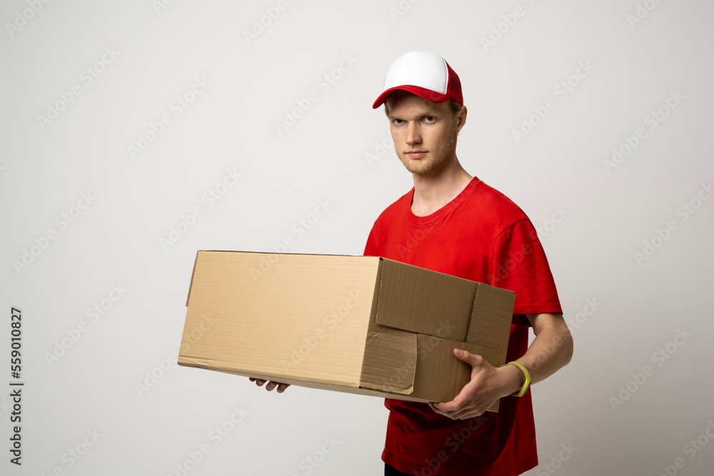 Courier man in red uniform carrying a box, parcel on white background. Delivery service, post. Courier man in red uniform carrying a box, parcel on white background. Delivery service, post.