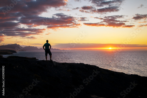 Man looks at the evening over the sea and the bright shining sunset on the Canary Islands in the evening light