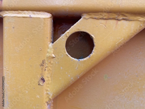 a yellow painted metal crossbar with hole diagonally in a corner