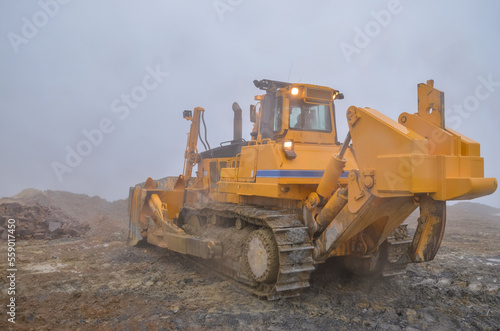 Big crawler dozer working on construction site or quarry. Mining machinery moving clay, smoothing gravel surface for new road. Earthmoving, excavations, digging on soils © Leszek Szelest