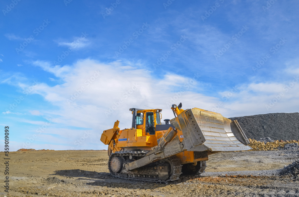 Big crawler dozer working on construction site or quarry. Mining machinery moving clay, smoothing gravel surface for new road. Earthmoving, excavations, digging on soils