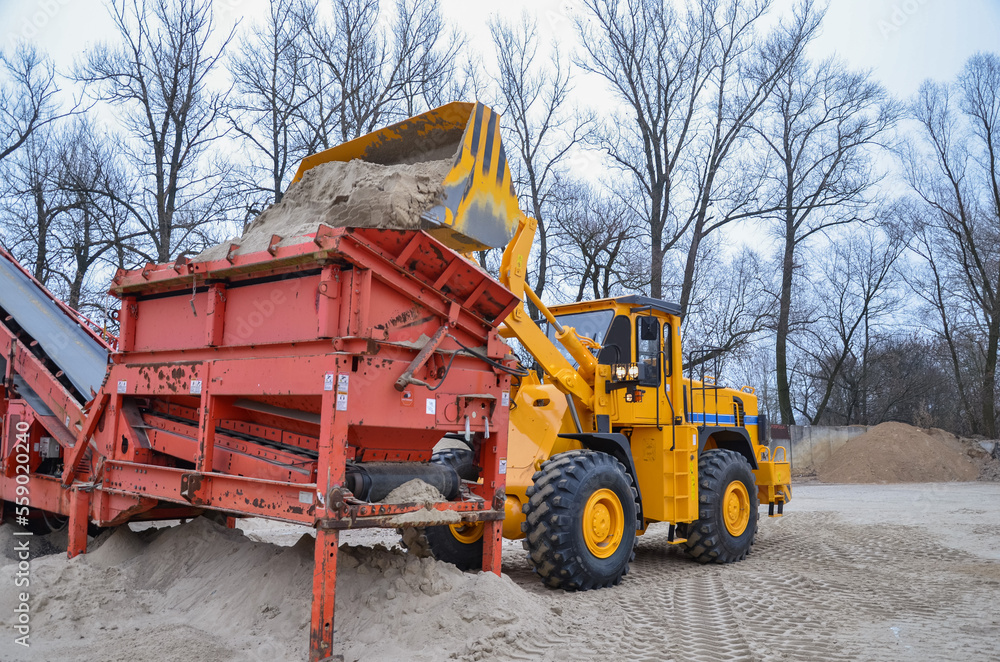 Wheel loader working in a gravel pit. Mining machines moving clay, smoothing the surface of gravel for a new road. Earthworks, excavations, digging in the ground, loading of charging baskets Wheel loader working in a gravel pit. Mining machines moving clay, smoothing the surface of gravel for a new road. Earthworks, excavations, digging in the ground, loading of charging baskets