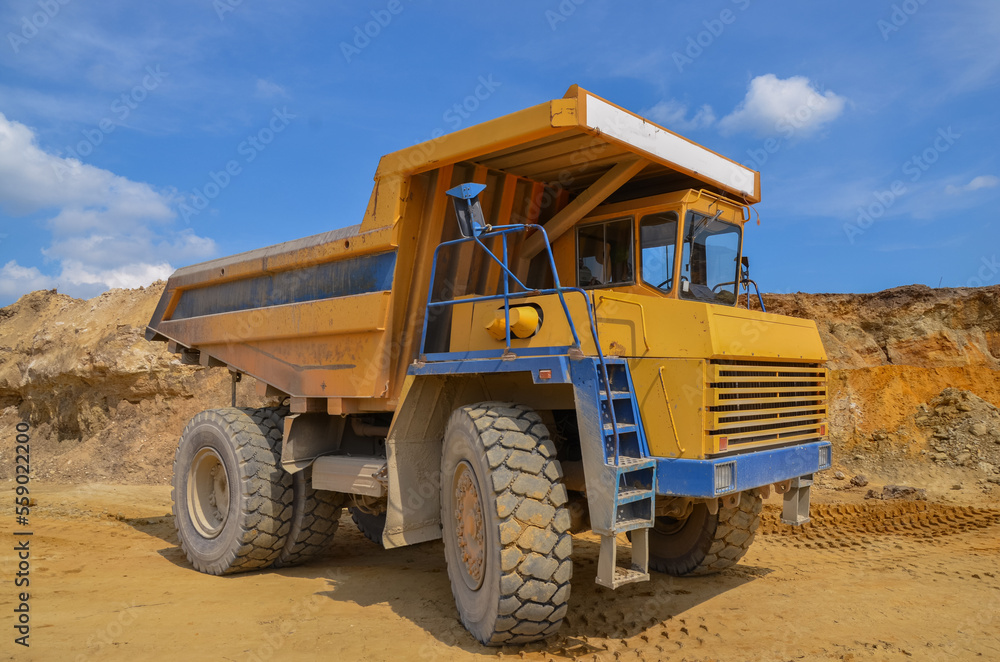 Large dumper truck working in a quarry on bright sunny day Large dumper truck working in a quarry on bright sunny day