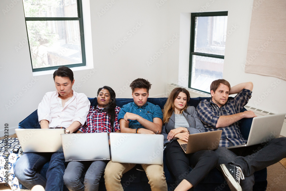 Tired business people using laptop while reclining on sofa in office Tired business people using laptop while reclining on sofa in office