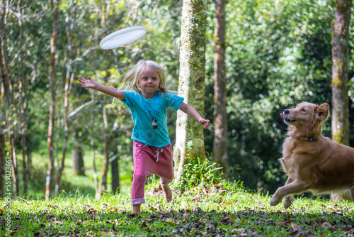 Little girl playing frisbee with her dog in park, Bedugul, Bali, Indonesia