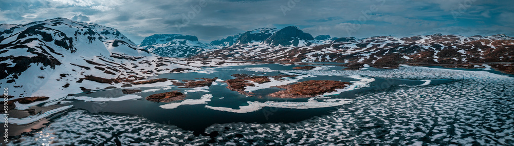 Snowy landscape of Hardangervidda national park with mountains and icy lakes in Norway, from above