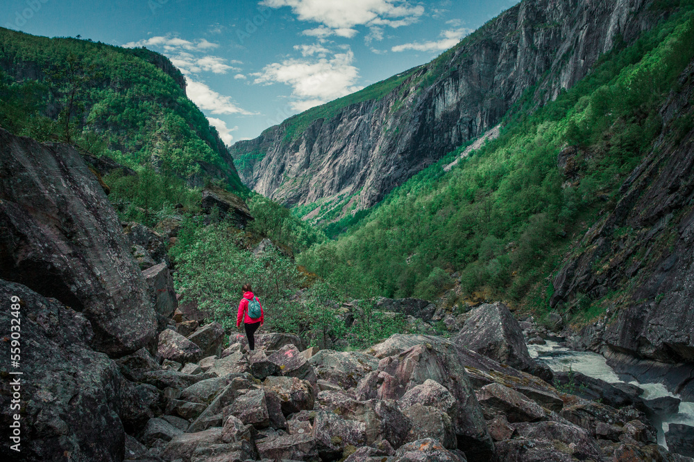 Woman hiking along river in the valley of Voringsfossen waterfall at Hardangervidda National Park in Norway