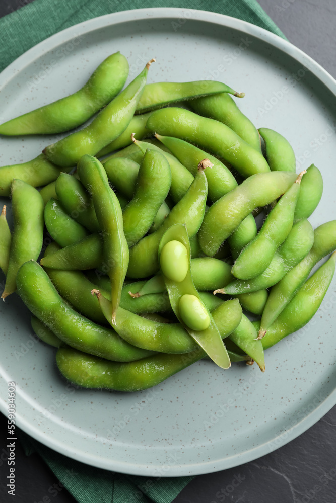 Plate of green edamame beans in pods on black table, top view Plate of green edamame beans in pods on black table, top view
