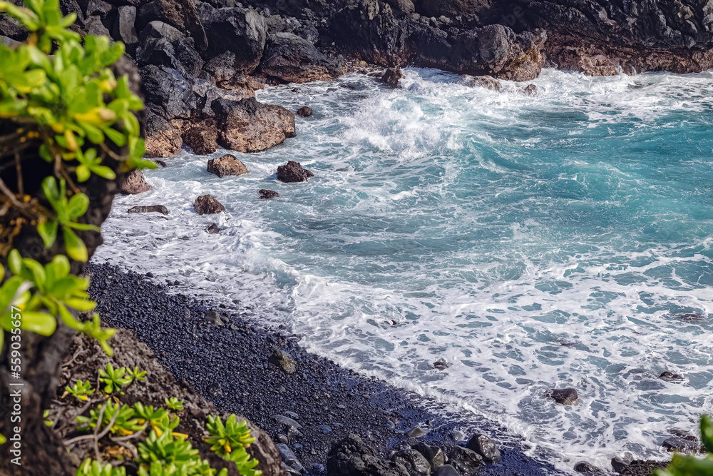 Small isolated beach with black stones on Maui island, Hawaii