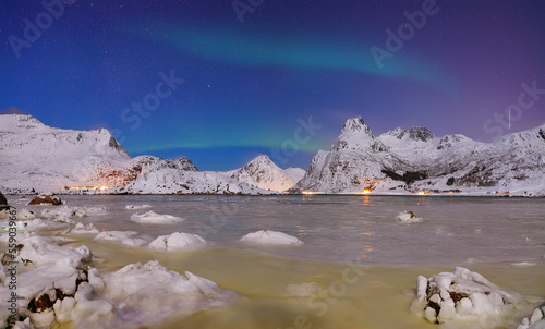 Fabulous frozen Flakstadpollen and Boosen fjords with Northern Lights at night. photo
