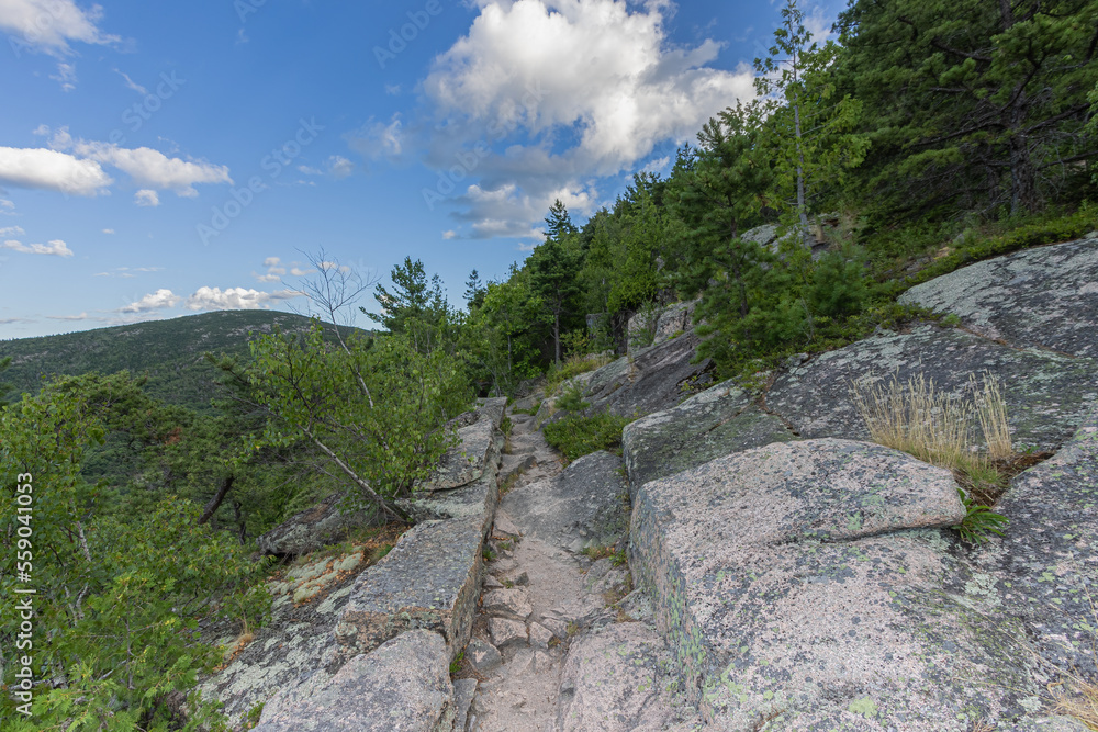 Rocky Hiking Path Landscape In The Tree Covered Mountains Of Maine State, New England, USA With Beautiful Clouds In The Blue Sky.