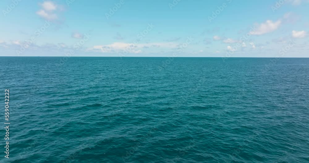 Aerial view of surface of blue ocean with waves and blue sky with cloud, aerial view. Water cloud horizon background. Blue sea water with waves against sky. Aerial view of surface of blue ocean with waves and blue sky with cloud, aerial view. Water cloud horizon background. Blue sea water with waves against sky.