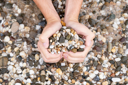 A man makes a heart out of pebbles. Heart on the sea. Romantic photo. Holiday on February 14 on a journey to the ocean.