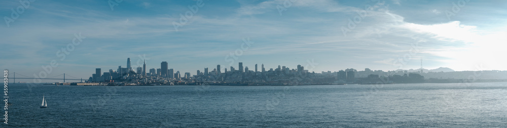 The Bay Bridge and San Francisco Skyline Panorama with sail boat. Views from Alcatraz Island on a foggy day - muted blue tones