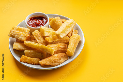A portion of fried maniocs ( Mandiocas ) on a on a Yellow background, traditional brazilian food photo