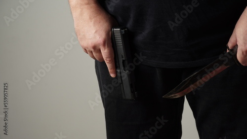 Male hands holding combat black Knife and a gun