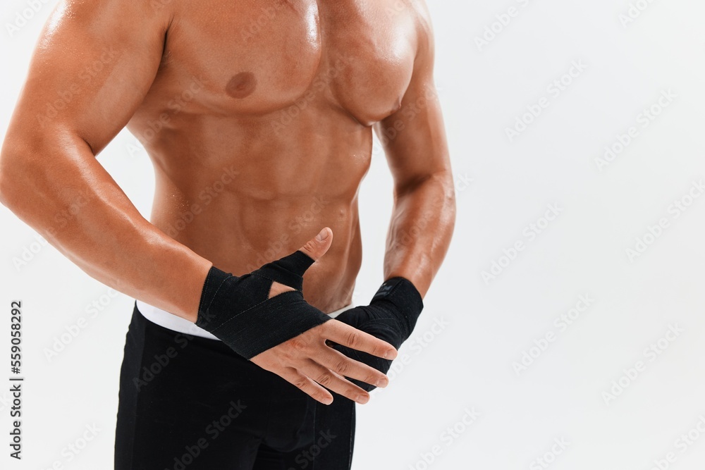 Naklejka premium Man athletic bodybuilder poses in boxing gloves with nude torso abs in full-length background, boxing and martial arts. Advertising, sports, active lifestyle, competition, challenge concept. 
