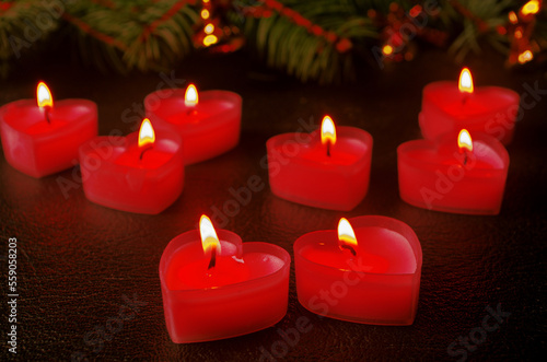 Lighted candles in the form of red hearts on a dark background.