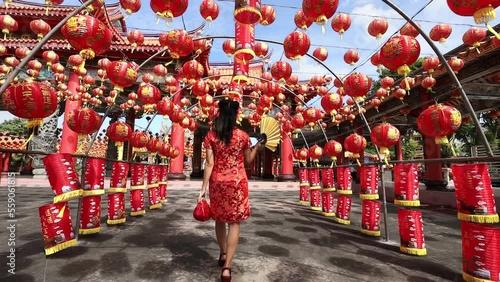 Rear view of Asian woman in red cheongsam qipao dress is visiting the Chinese Buddhist temple during lunar new year for traditional culture concept the Chinese word means blessing for all